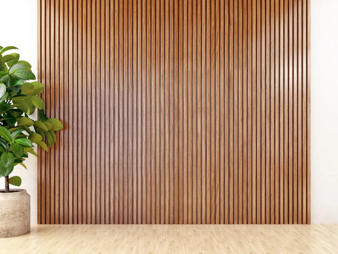 Modern vertical wood slat feature wall with potted plant in a minimalist room.